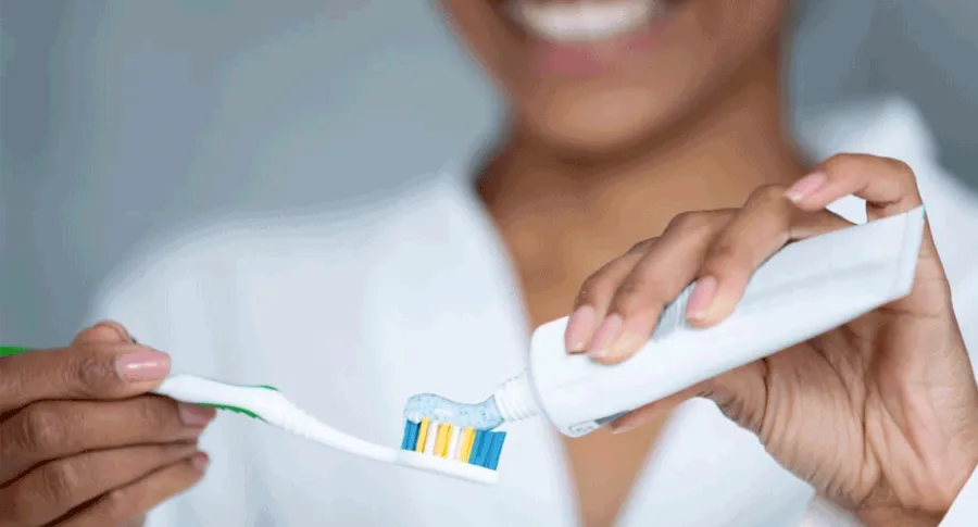 woman putting toothpaste on brush