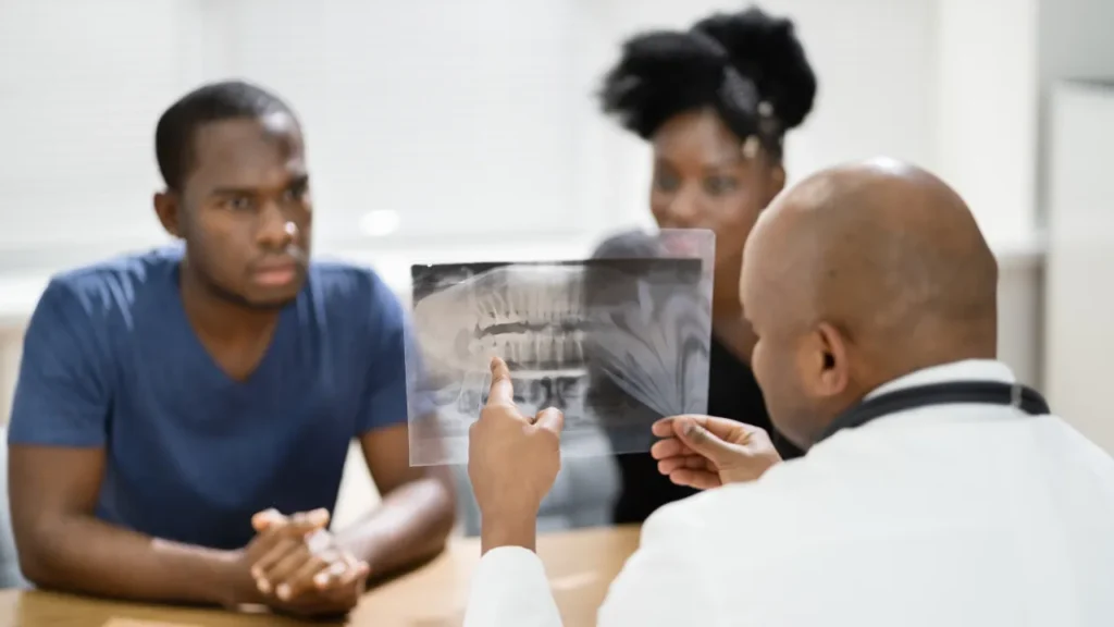 Black dentist showing x-ray to two black patients